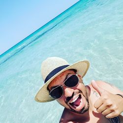 Portrait of man wearing sunglasses and hat in sea during summer