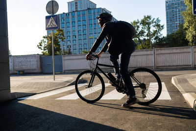 Rear view of man riding bicycle on street