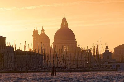 Buildings by sea against sky during sunset