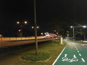 Illuminated road against sky at night