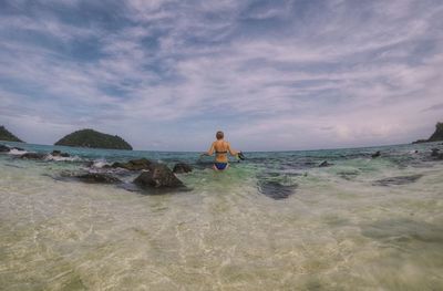 Rear view of shirtless man in sea against sky