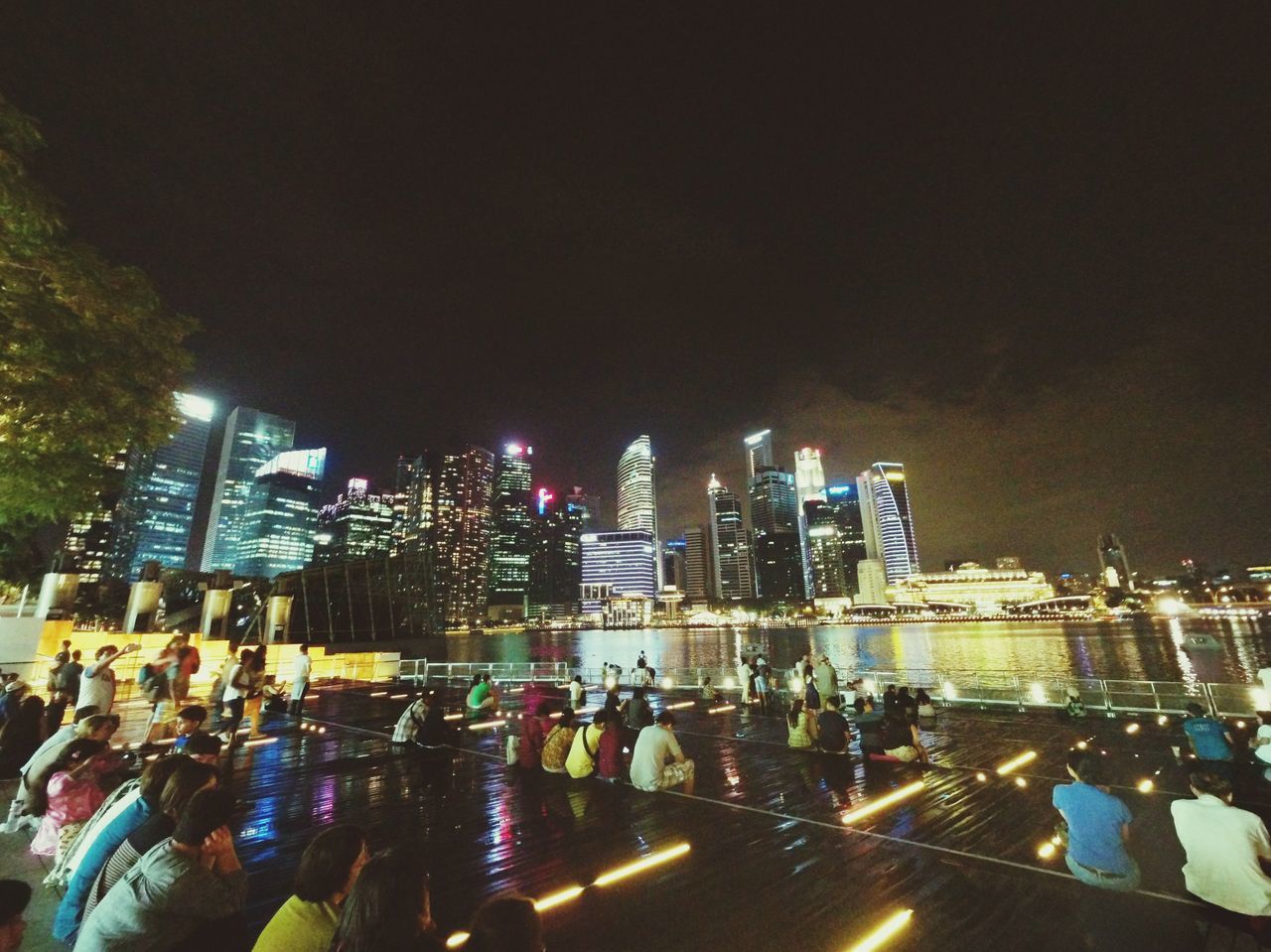 illuminated, night, building exterior, city, architecture, built structure, skyscraper, city life, tall - high, cityscape, modern, office building, large group of people, tower, street, urban skyline, financial district, high angle view, crowded