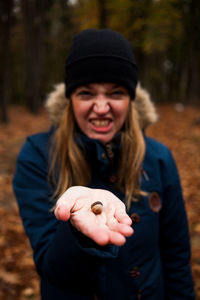 Portrait of young woman holding acorn at forest