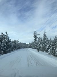 Road amidst snow covered trees against sky