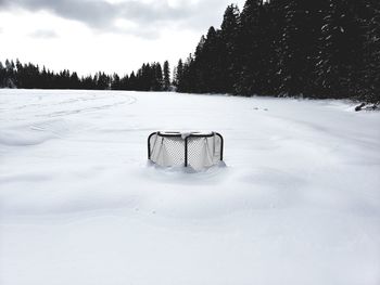 Bicycle on snow covered field against sky