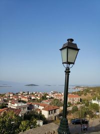 Street light amidst buildings against clear blue sky