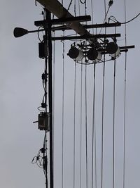 Low angle view of silhouette telephone pole against sky