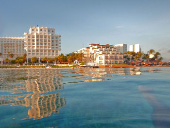 Buildings by swimming pool in sea against sky