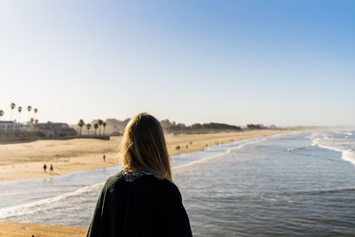 Rear view of woman looking at sea against clear sky