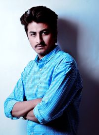 Portrait of young man with arms crossed standing against wall