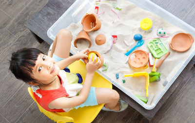 High angle view of cute boy holding toy on table