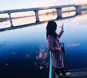 Rear view of woman standing by railing