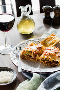 A serving of lasagna roll ups with red wine, parmesan cheese and garlic toast.