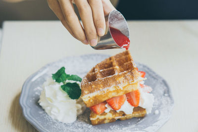 Close-up of hand holding ice cream in plate