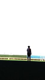 Rear view of man with woman standing against clear sky