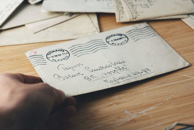 Cropped hand of woman holding letter on table