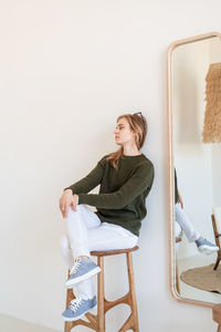 Minimal light and airy interior design. attractive young woman in white jeans and green sweater 