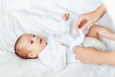 Cropped hand of mother wearing clothes to baby