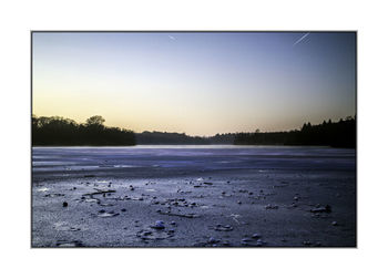 Scenic view of lake against clear sky at sunset