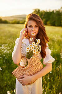 Portrait of smiling young woman standing against plants