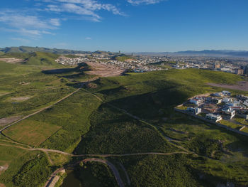 Aerial view of agricultural field by buildings against sky