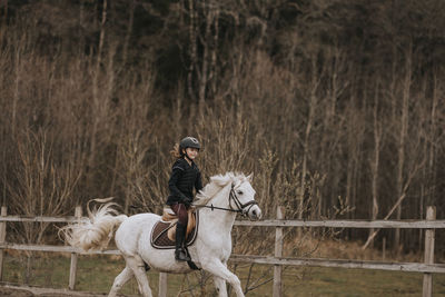 View of girl horseback riding