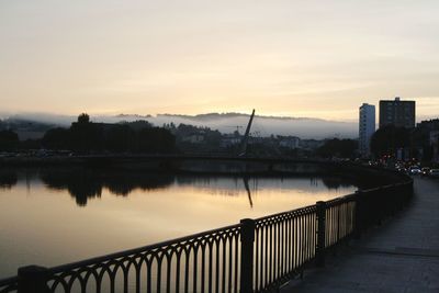 Bridge over river against sky during sunset