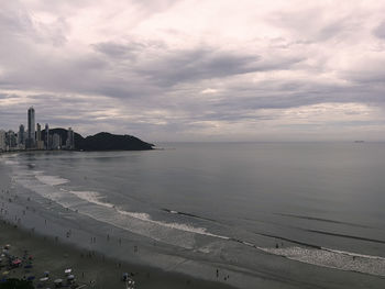 Oceanic and tourist coast, with big buildings, gray morning, rain, people walking