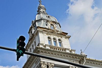 Low angle view of arrow sign and historic building against sky