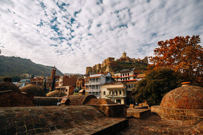 Buildings in town against cloudy sky