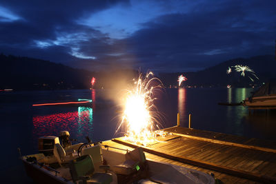 Fireworks exploding on pier by lake at night