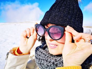 Portrait of woman wearing sunglasses at beach during winter