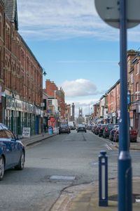 Cars on street in city against sky