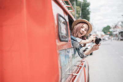 Woman holding red umbrella at bus