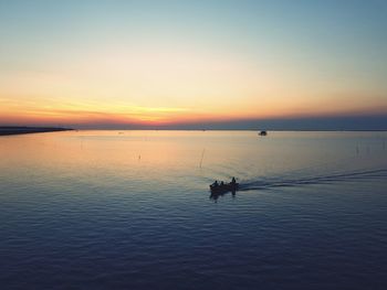 Silhouette person in sea against sky during sunset