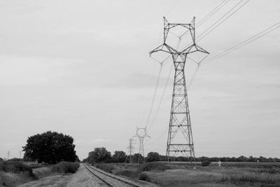 Electricity pylons on field against sky