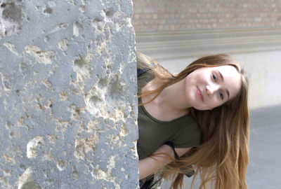 Portrait of a smiling young woman against wall