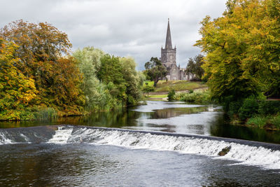 River amidst trees and buildings against sky