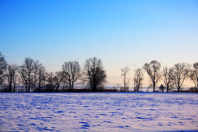 Snow covered field against clear sky