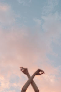 Low angle view of person hand against sky during sunset