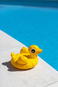 Inflatable yellow mini duck, cocktail stand near swimming pool on bright sunny day, copy space.