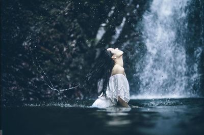 Side view of a woman splashing water in forest