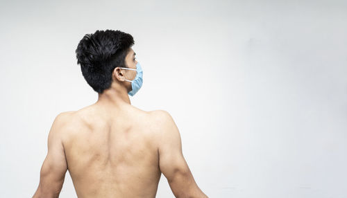 Rear view of shirtless man against white background