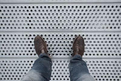 Low section of man standing patterned metallic floor