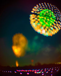 Defocused image of illuminated lights against sky at night