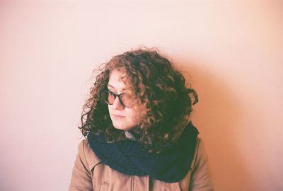 Thoughtful young woman standing against wall