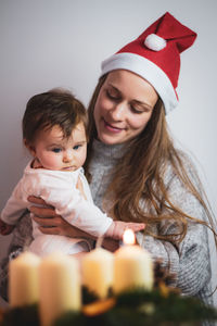 Portrait of smiling young mother holding her baby at christmas time