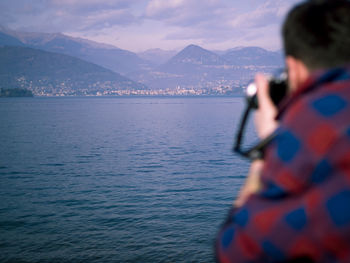 Rear view of woman photographing sea against sky