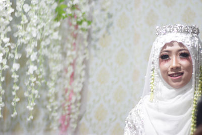 Portrait of smiling woman standing against wall