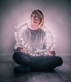 Young man wearing illuminated lights while sitting at home